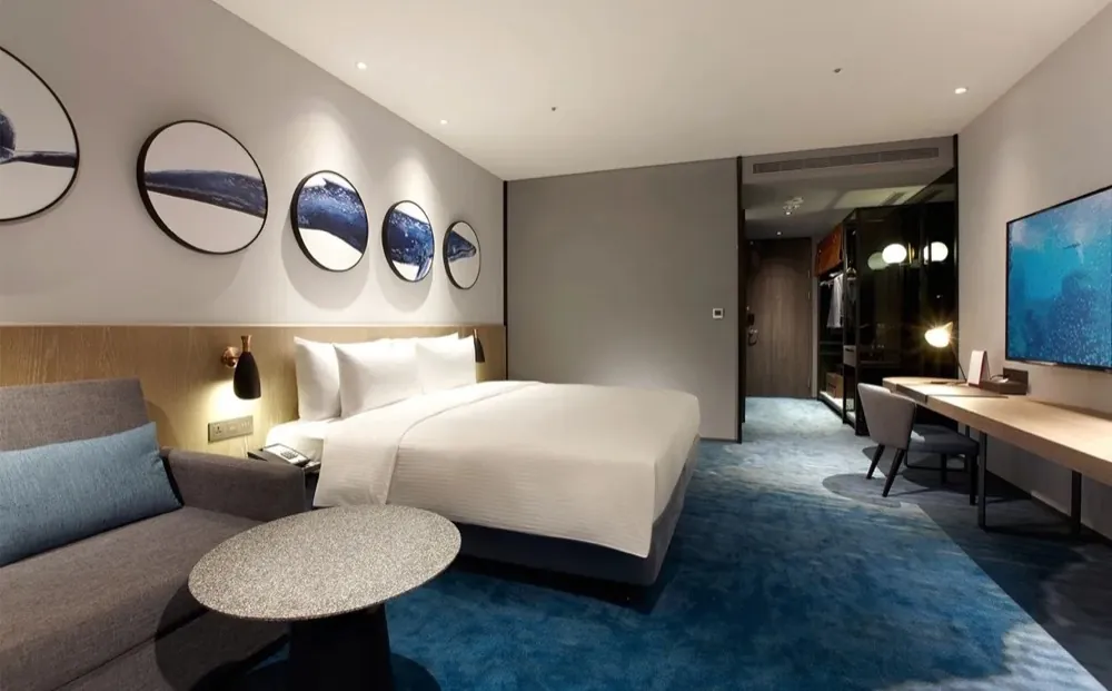 A king room at COZZI Blu Taoyuan with an ocean-pattern carpet and whale art plates on the wall.