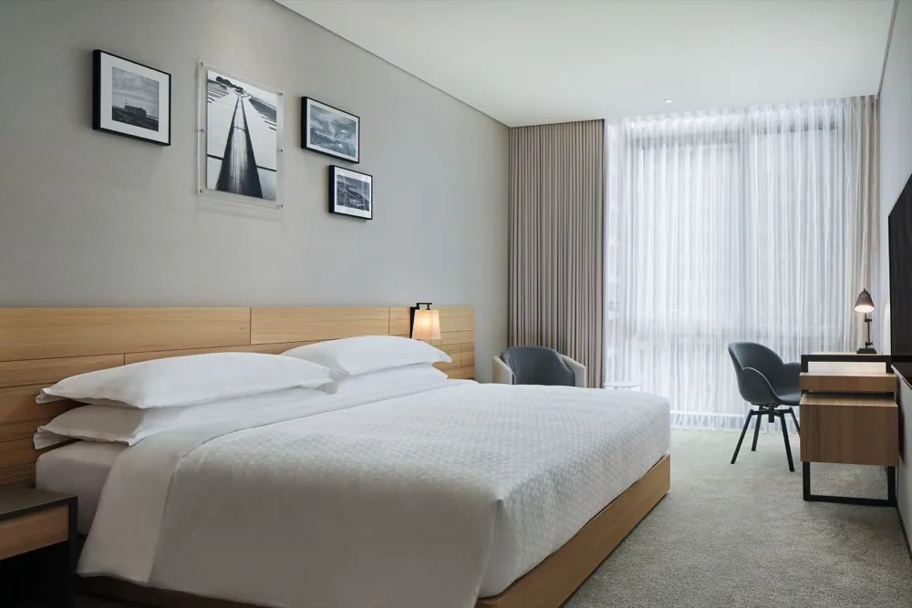 A bright king room at Four Points by Sheraton Linkou with a light oak headboard and sheer curtains.