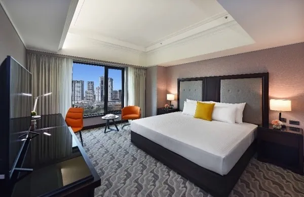 A king room at Fullon Poshtel Linkou with two orange armchairs by a window over the Linkou skyline.