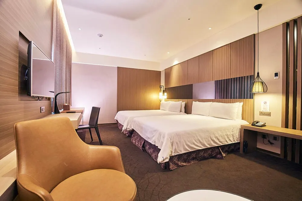 A twin room at Hotel Intrendy with wood-slat walls and a leather armchair.