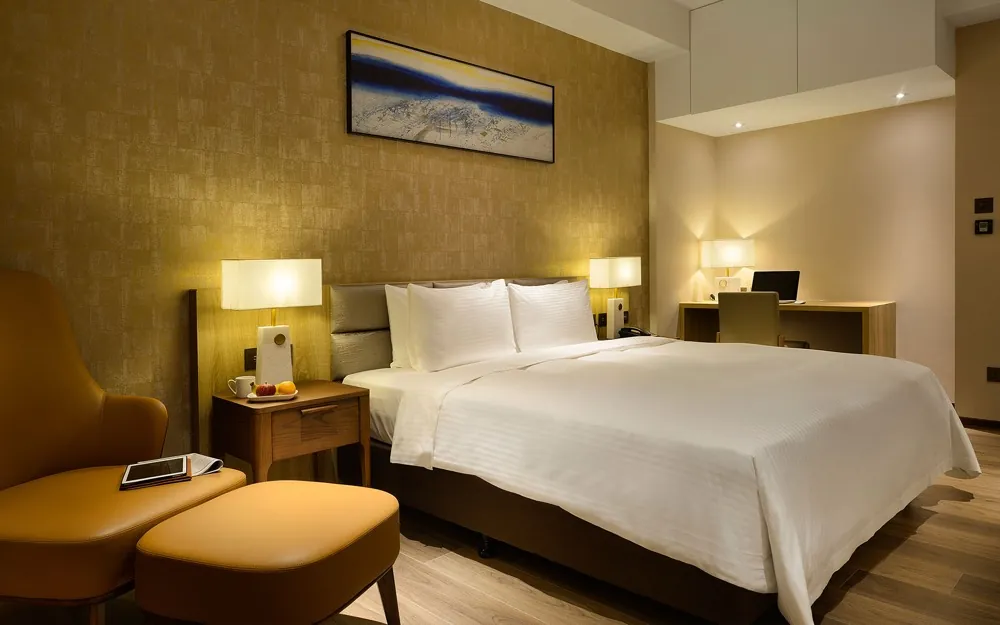 A warm king room at Joyfultel with gold textured wallpaper and a lounge chair.